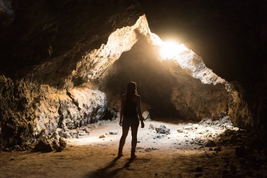 Woman standing in cave with light shining in